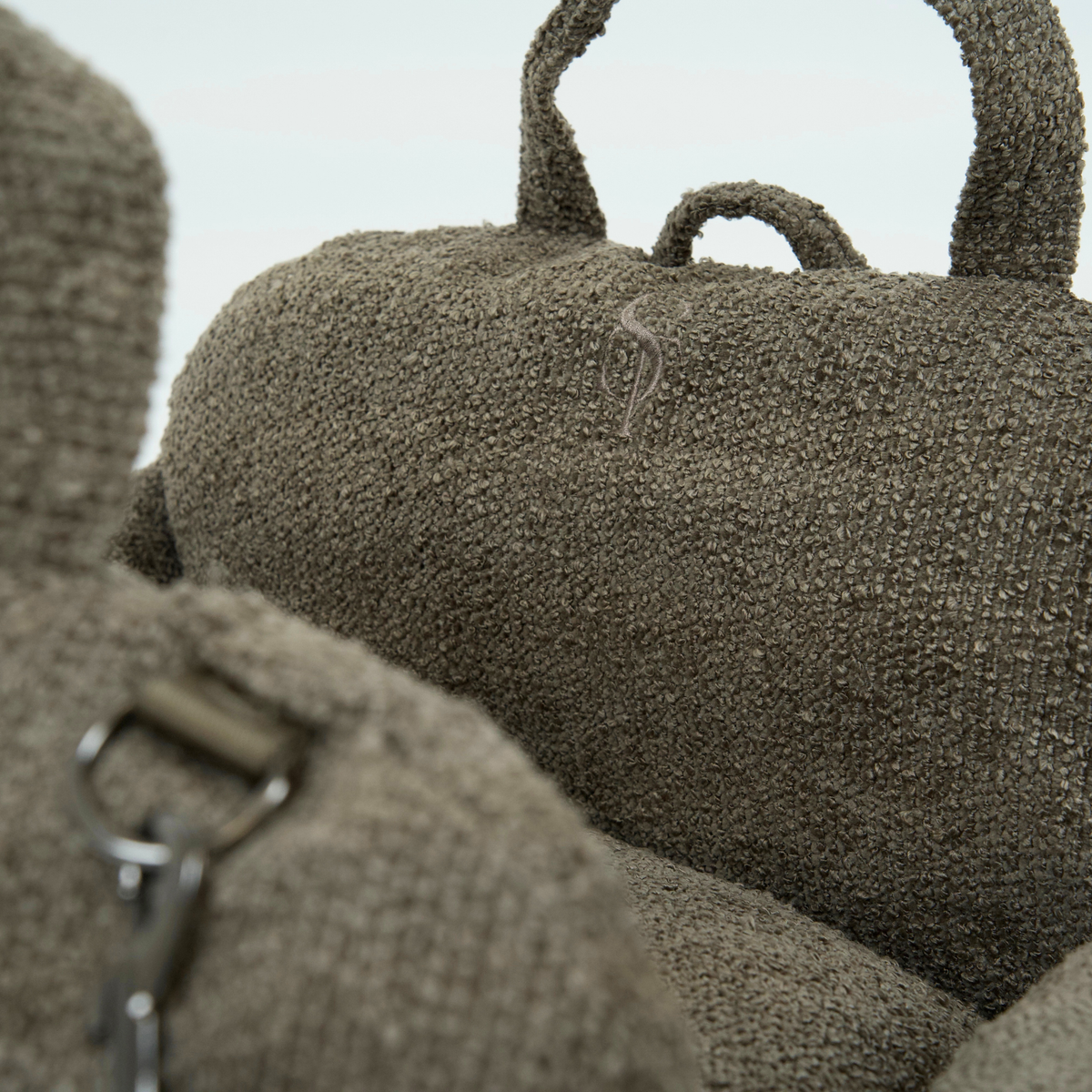 Close-up of the carry handle and safety leash on a brown bouclé dog car seat