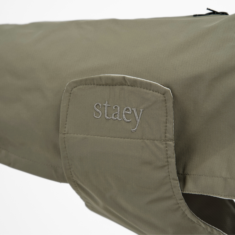 Close-up of the embossed Staey wordmark on the olive green rain coat collar