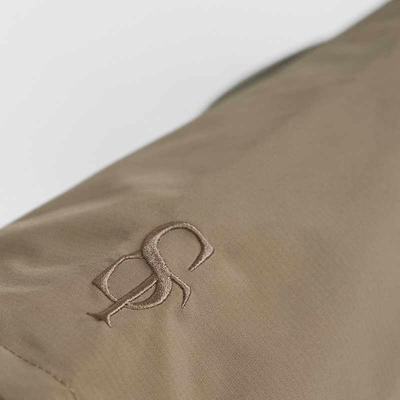 Close-up of the embossed Staey monogram on the taupe dog rain coat