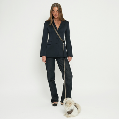 Woman walking a small white dog on the taupe hands-free leash
