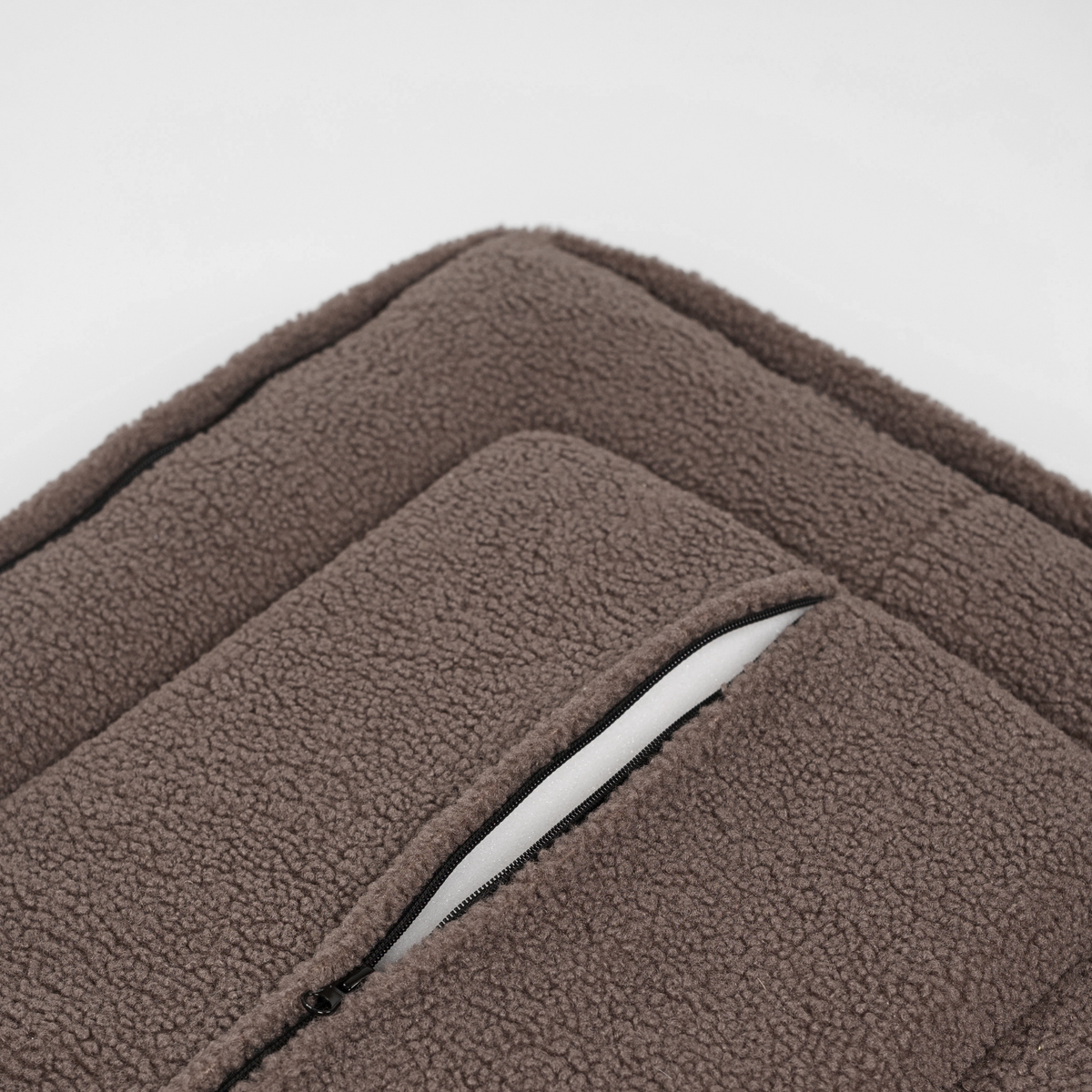 Close-up of the zip along the edge of the taupe teddy dog bed
