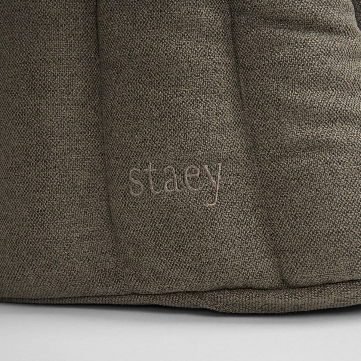 Close-up of the embossed Staey wordmark on the olive teddy carrier bag