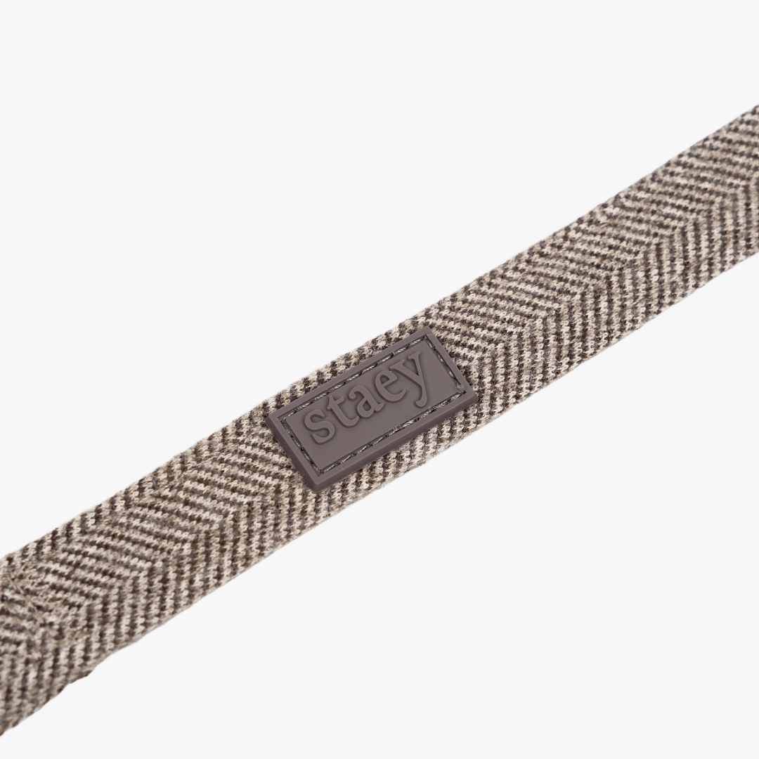 Nahaufnahme des mocca-farbenen Herringbone-Gurtbands und des Staey-Etiketts